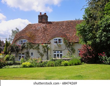 Traditional English Village Cottage And Garden With Climbing Roses On The Wall