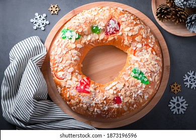 Traditional Epiphany cake Roscon de Reyes on grey stone table top with small Christmas tree and decoration closeup, top view