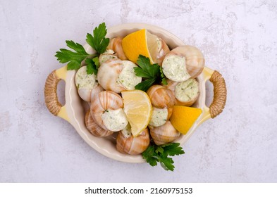 Traditional Escargot With Spicy Butter In A Ceramic Dish With Lemon And Parsley. Selective Focus. Top View.