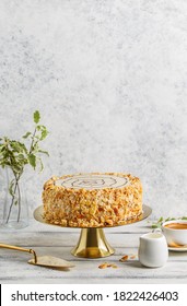Traditional Esterhazy cake with almond on golden cake stand over white background with cup of coffee and cake spatula. Side view, copy space