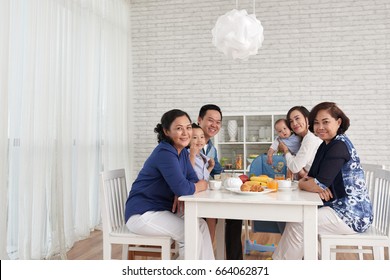 Traditional Family Values: Portrait Of Big Asian Family Gathering At Dinner Table And Looking At Camera, Smiling