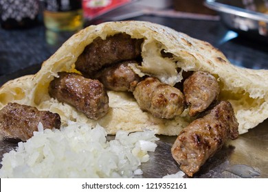 Traditional fast food from Balkan cuisine - juicy cevapi made of minced meat and served with fresh onion in a special bun, lepinja or somun