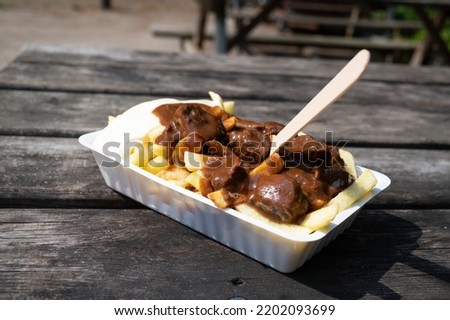 Traditional fast and street food in Belgium, French fried potatoes with beef stew and mayonnaise in plastic box outdoor