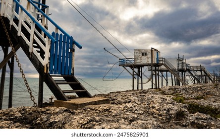 Traditional fisherman huts on stilts with carrelet fishing net at Saint-Palais rocky beach on the coast of France. Wooden houses for fishing - Powered by Shutterstock