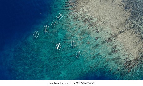 Traditional fishing boats float over the clear blue and turquoise waters of Bali, showcasing the stunning coral reefs below.
 - Powered by Shutterstock