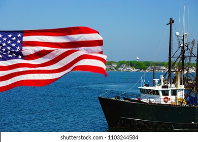 A Traditional Fishing Trawler Boat With The American Flag In Foreground. Commercial Fishing Remains An Iconic Industry Of Several Coastal States In New England.