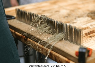 Traditional flax processing with hackling tool on wooden table for craft and textile design. - Powered by Shutterstock