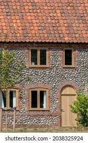 Traditional flint pebble faced cottage in rural Norfolk UK. Close-up of a beautifully restored old flint faced building made from local materials. Traditional pebble dashed vintage English house.