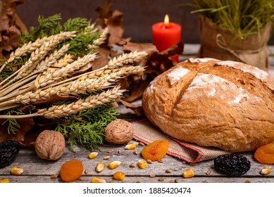 Traditional food for orthodox Christmas eve. Yule log or badnjak, bread, cereals, dried fruits and burning candle on wooden table. Concept celebration orthodox Christmas.