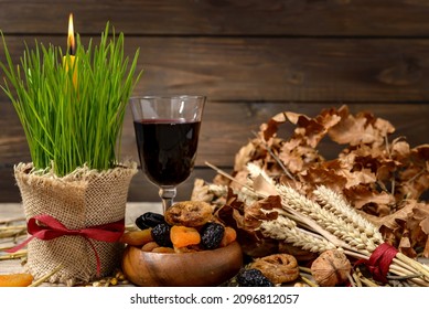 Traditional food for orthodox Christmas eve. Yule log or badnjak, wine, apples, cereals, dried fruits and burning candle on wooden table. Concept celebration orthodox Christmas.