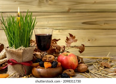 Traditional food for orthodox Christmas eve. Yule log or badnjak, wine, apple, cereals, dried fruits and burning candle on wooden table. Concept celebration orthodox Christmas.