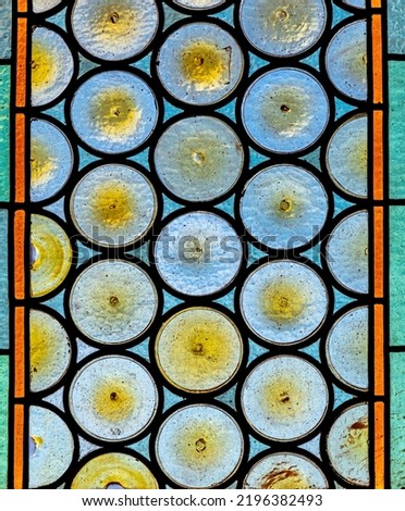 Traditional French chateau window made of circular tinted glass forming an interesting pattern and texture suitable for backgrounds or wallpapers