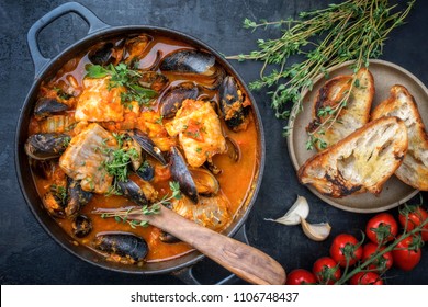 Traditional French Corsican fish stew with mussels with garlic baguette as top view in a pot