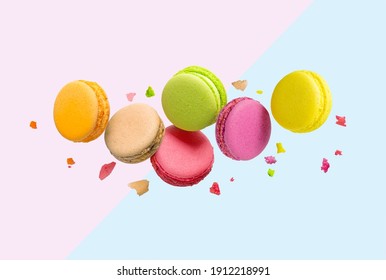 Traditional french multicolored macaroons falling on pink and blue background