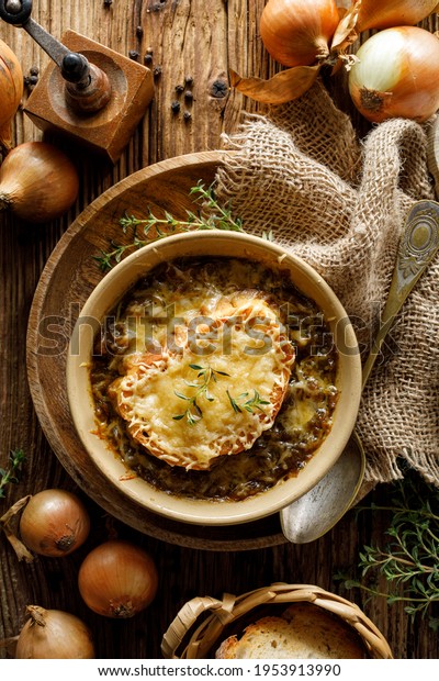 Traditional French onion soup baked with
cheese crouton sprinkled with fresh thyme, top
view.