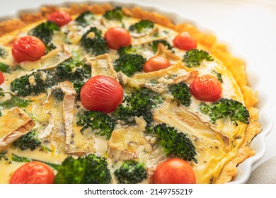 Traditional french pie. Quiche Loraine with mushrooms, broccoli, tomatoes and cheese. top view, in ceramic baking dish on heat-resistant stand. Vegetarian French Open Pie Quiche Lorraine