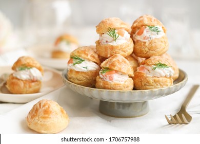 A traditional French savory choux dough cheese puff filled with fresh cheese mixed with smoked salmon in a plate decoration with dill leaf. This pastry well know as spiciality of Burgundy - Shutterstock ID 1706757988