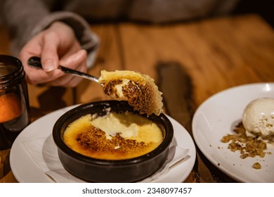 La crème brûlée tradicional francesa, servida en un restaurante francés y escopeta con cuchara