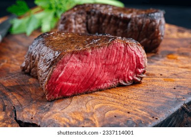 Traditional fried dry aged bison beef rump steak served as close-up in a rustic old wooden board 