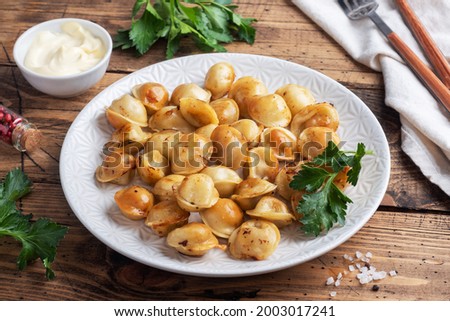 Traditional fried pelmeni, ravioli, dumplings filled with meat on plate, russian kitchen. Wooden rustic table, copy space