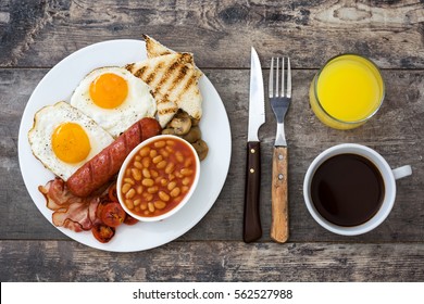 Traditional Full English Breakfast With Fried Eggs, Sausages, Beans, Mushrooms, Grilled Tomatoes And Bacon On Wooden Background.Top View
