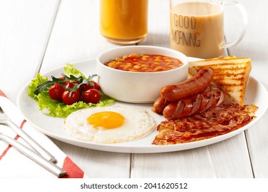 Traditional Full English Breakfast, On A White Background, Fried Eggs With Fried Bacon, Sausages, White Beans ,cherry Tomatoes, Horizontal, No People,