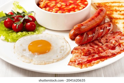 Traditional Full English Breakfast, On A White Background, Fried Eggs With Fried Bacon, Sausages, White Beans ,cherry Tomatoes, Horizontal, No People,