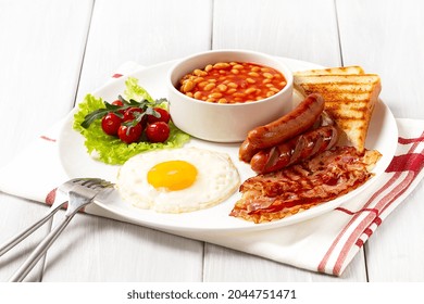 Traditional Full English Breakfast, On A White Background, Fried Eggs With Fried Bacon, Sausages, White Beans ,cherry Tomatoes, Horizontal, No People,