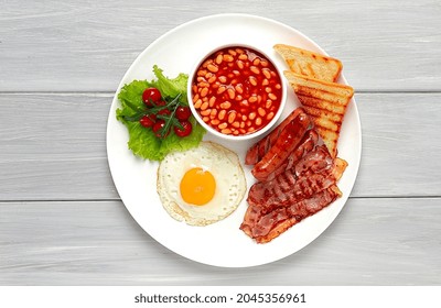 Traditional Full English Breakfast, On A White Background, Fried Eggs With Fried Bacon, Sausages, White Beans ,cherry Tomatoes, Horizontal, No People,