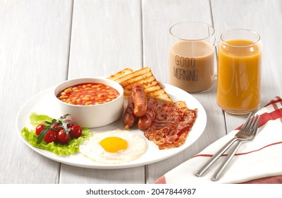 Traditional Full English Breakfast, On A White Background, Fried Eggs With Fried Bacon, Sausages, White Beans ,cherry Tomatoes, Horizontal, No People,