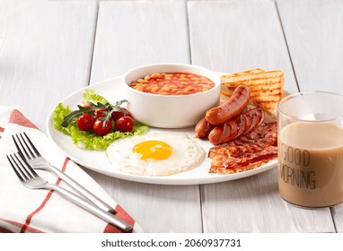 Traditional Full English Breakfast, On A White Background, Fried Eggs With Fried Bacon, Sausages, White Beans ,cherry Tomatoes, Horizontal, No People,