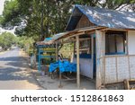 Traditional gas station on Java island in Indonesia. Wooden stand with gasoline in glass liter bottles ready for sale. Simple wooden house with bamboo shelter. Mesh instead of glass in windows.