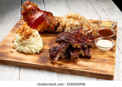 Traditional German beer snacks. Shank, stewed cabbage, fried ribs, mashed potatoes. On a wood panel
