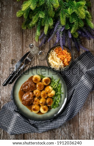 Traditional German braised pork cheeks in brown sauce with mushroom served with silesian dumplings.