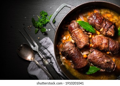 Traditional German Meal Of Beef Roulades In Roast Pot With Fresh Vegetables And Seasoning On A Kitchen Table