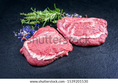 Traditional German raw beef cheeks offered as closeup on a black board with copy space 
