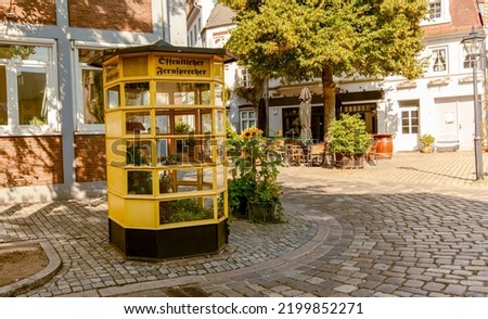 Traditional German telephone box with flowers. Old yellow telephone booth in Germany with text öffentlicher fernsprecher - public telephone