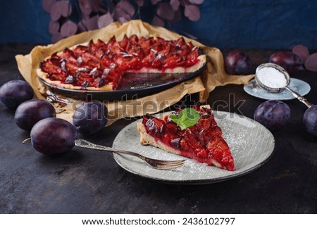 Traditional German zwetschgenkuchen with sliced plums served as close-up on Nordic design plate and a backing sheet with brown paper 
