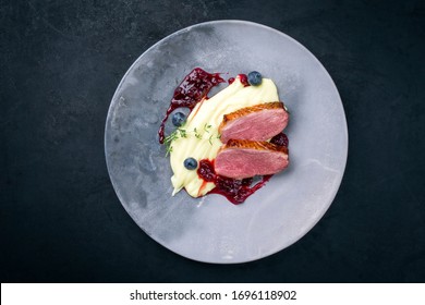 Traditional gourmet duck breast filet with mashed potatoes and cranberry sauce as top view on a modern design plate with copy space  - Powered by Shutterstock