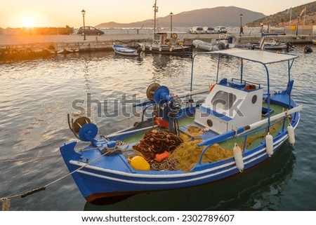 Traditional greek fishing boat with fighing nets moored in the harbour at Agia Effimia at sunset, Kefalonia, Ionian sea, Greece.
