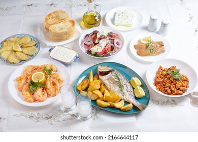 Traditional  Greek food, Dorada fish with Greek salad, Mediterranean traditional menu, Grilled sea bream, shrimps, zucchini, variety of seafood, mussels, tzatziki, potatoes, feta and ouzo