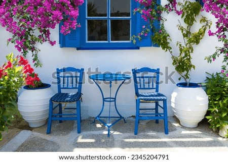 traditional greek home outdoor scenery with front yard, greek style table and chairs and blooming flowers and bougainvillea