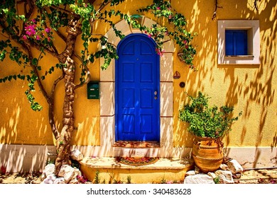 Traditional greek house with blue doors and yellow wall