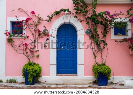 Traditional greek house with colorful blue door and pink walls at Asos village. Assos peninsula famous and extremely popular travel destination in Cephalonia, Greece, Europe.