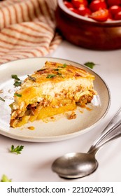 Traditional Greek Moussaka With Eggplant, Zucchini And Béchamel Sauce With Cinnamon Spiced Meat Filling And Potato Layer Served On A Plate With Lot Of Cheese