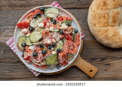 Traditional greek salad with feta cheese, peppers, black olives, cucumber, tomatoes and onions  on a plate on wooden table background. Choriátiki saláta - Powered by Shutterstock