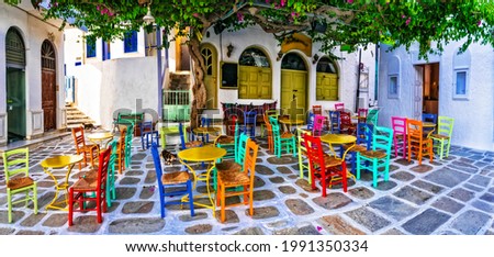 Traditional Greek taverns on the streets. Ios island, old town Chora. Restaurant with colorful typical chairs. Cyclades, Greece