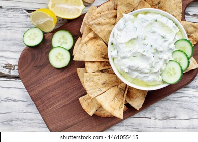 Traditional Greek Tzatziki dip sauce made with cucumber sour cream, Greek yogurt, lemon juice, olive oil and a fresh sprig of dill weed. Served with toasted Za'atar Pita bread.  Top view  or flat lay.