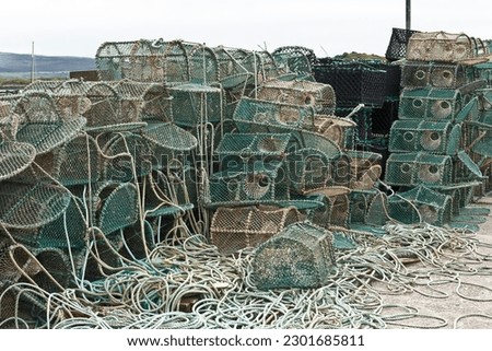 Traditional green lobster traps or lobster pots with ropes stacked up on a concret quay in Tobermory, Isle of Mull, Hebrides, Scotland.