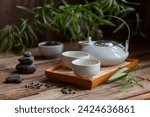 Traditional green tea ceremony set - white teapot and cups with stones piramide, house for the soul, on the tray
